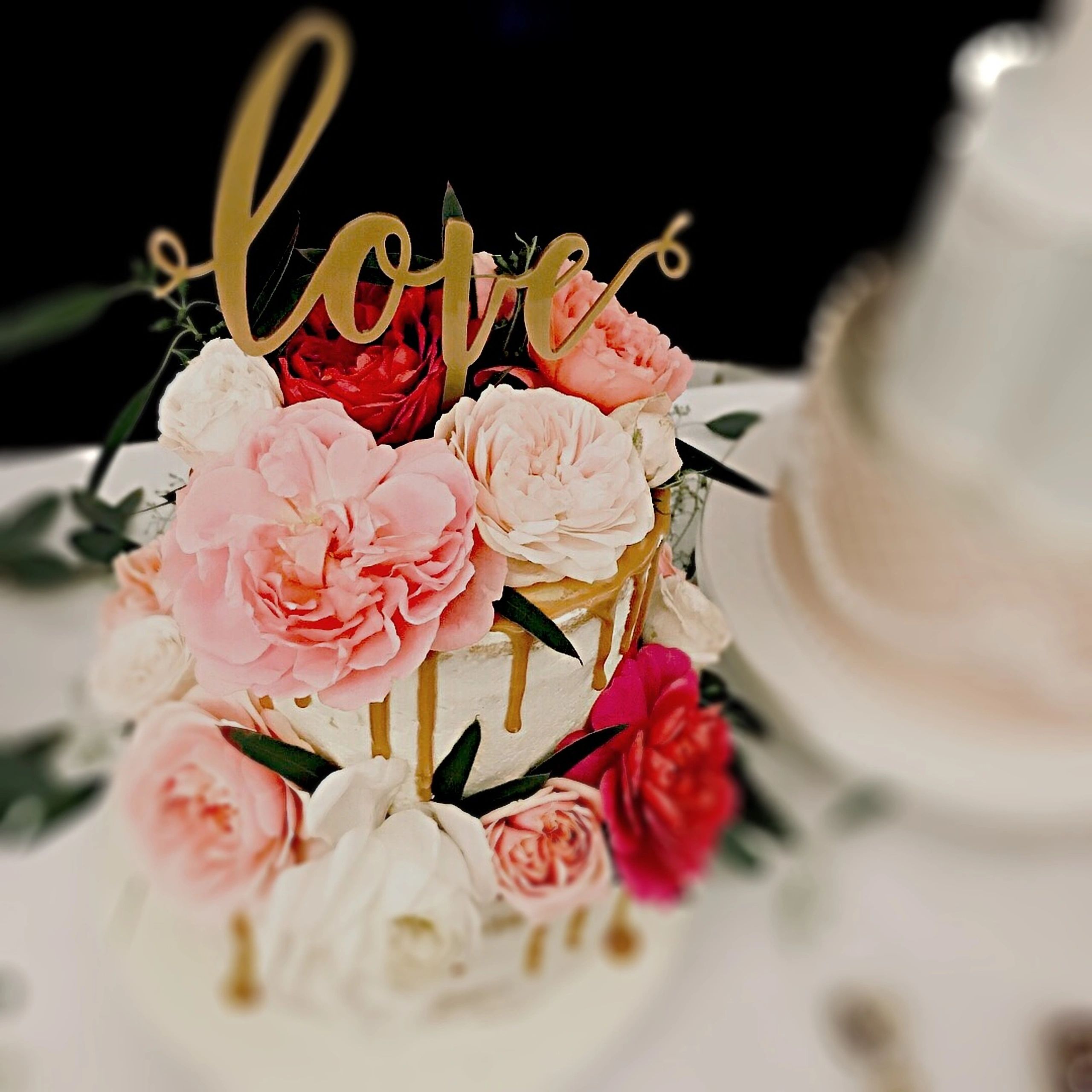 Close-up of wedding cake with flowers and gold icing