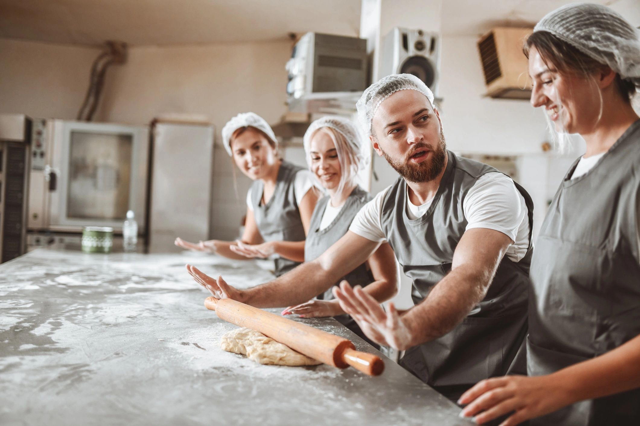Baker teaching an apprentice to use a rolling pin