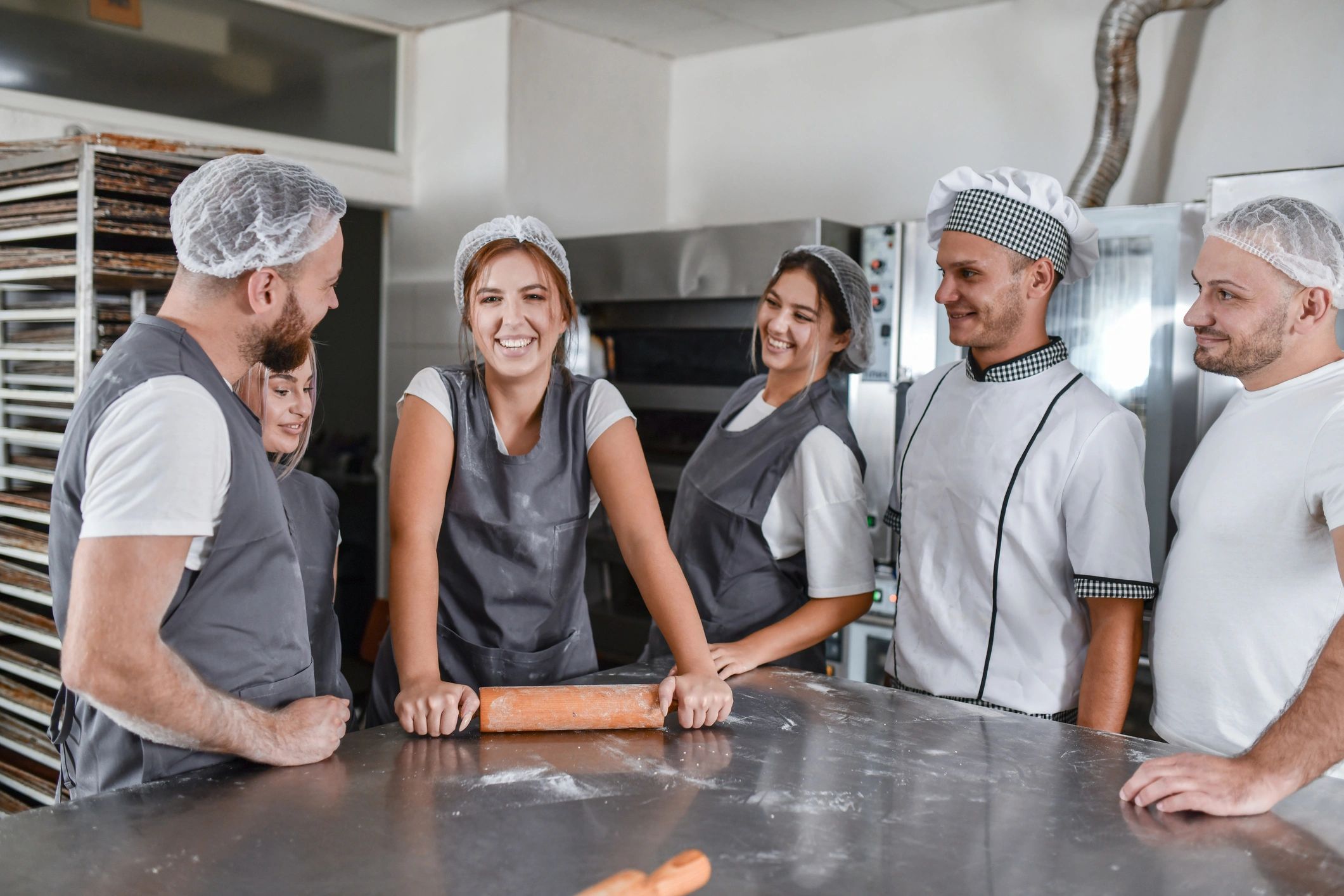 Baker preparing dough with a rolling pin in a bakery