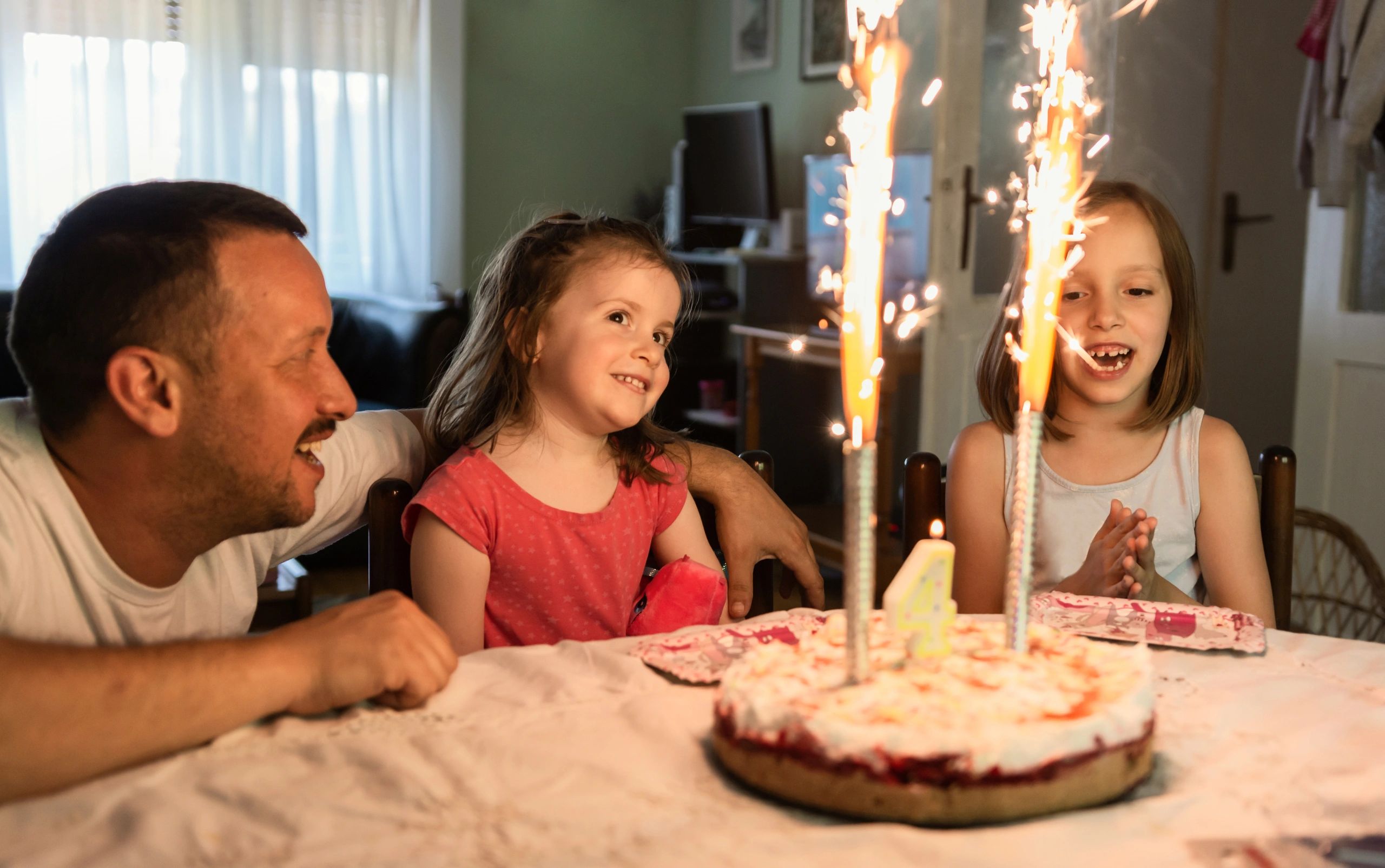 Family singing happy birthday to a girl at home
