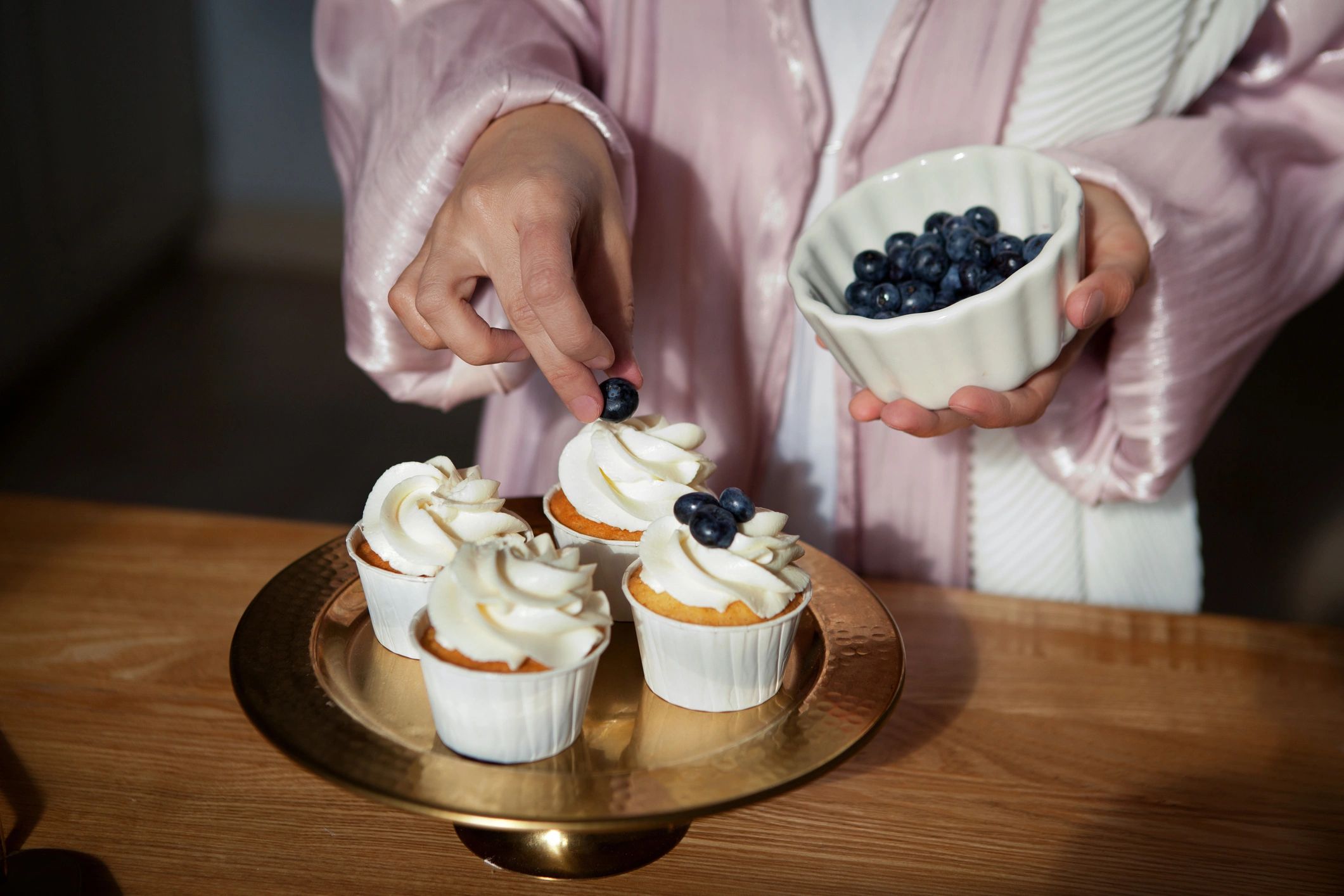 Hands decorating cupcakes with fresh berries