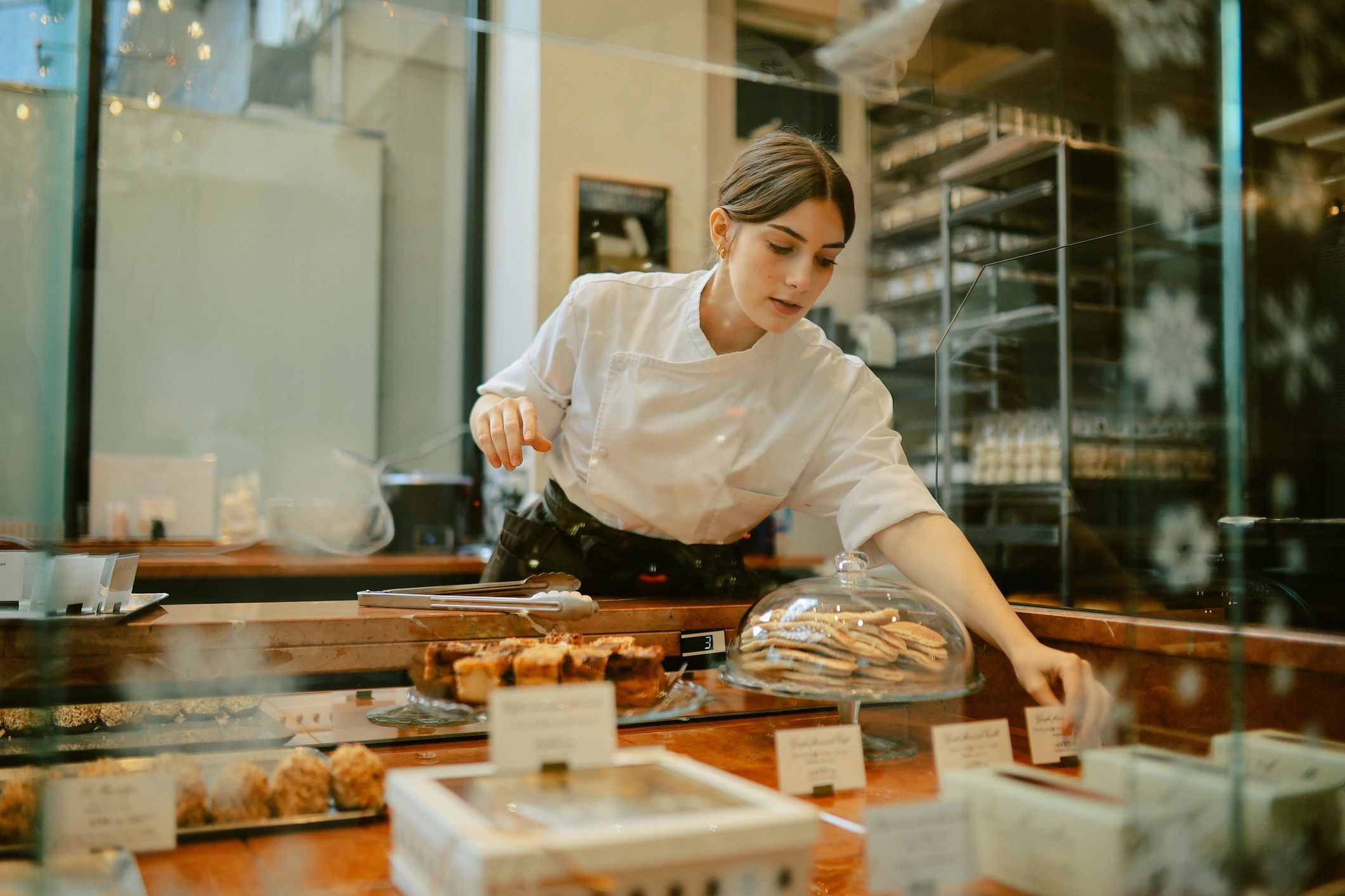 Bakery owner arranging cakes in a patisserie