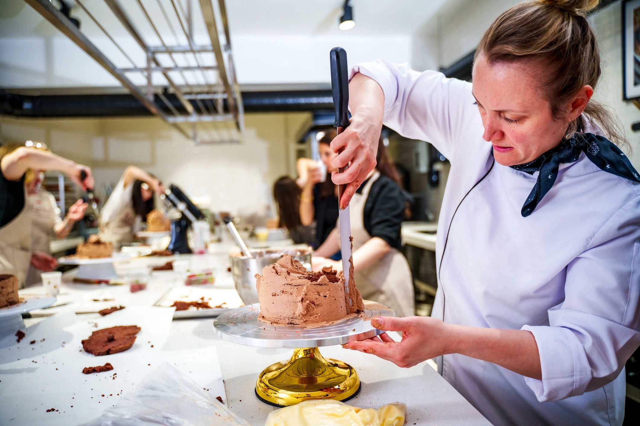 Baker decorating a cake in a professional kitchen