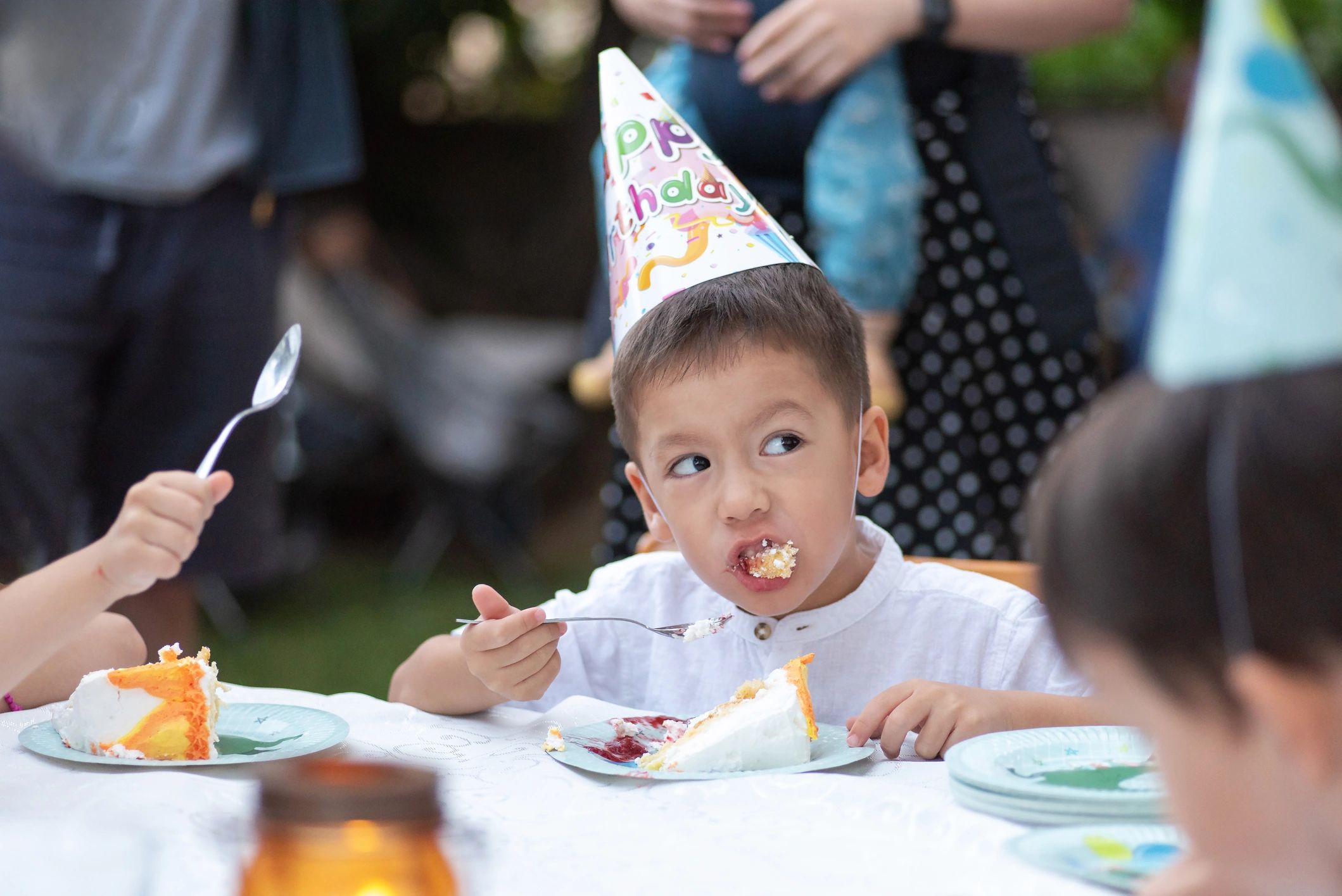 Young boy enthusiastically eating cake at his birthday party
